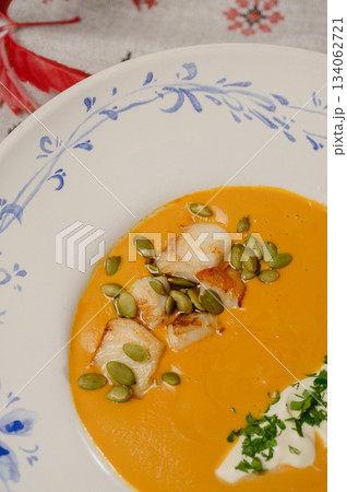 Pumpkin cream soup with seeds, cream, and parsley on a plate Pumpkin cream soup with seeds, cream, and parsley on a plate 134062721