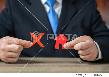 Businessman holding a prohibition sign over a house Businessman holding a prohibition sign over a house 134062797