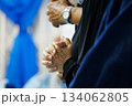 Close-up of a believer clasping their hands in prayer during worship. Soft lighting and added film grain create a classic, emotional atmosphere. Suitable for themes of faith, spirituality, devotion 134062805