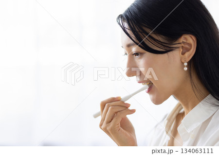 窓からの光を浴びながら歯磨きをする女性のクローズアップ 134063111
