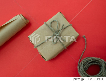 Packing of New Year's gifts Gift, twine, paper on a red background. Packing of New Year's gifts Gift, twine, paper on a red background. 134063901