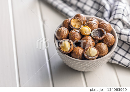 Tasty macadamia nuts in bowl on white table. 134063960