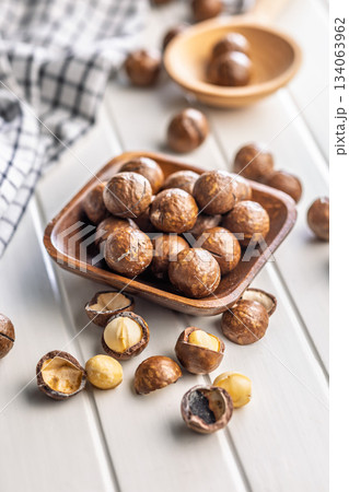 Tasty macadamia nuts in bowl on white table. Tasty macadamia nuts in bowl on white table. 134063962