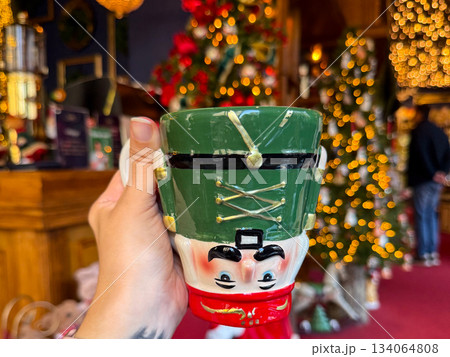 Christmas Nutcracker mug held in a festive holiday shop. Seasonal joy, playful tradition and warm winter storytelling enhancing decorative atmosphere and charming holidays celebration 134064808