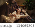 Couple enjoys intimate moment on a couch with soft lighting and greenery in the room 134065203