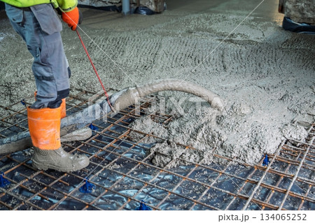 Concrete Pouring on Construction Site with Worker Leveling and Reinforcement Grid Concrete Pouring on Construction Site with Worker Leveling and Reinforcement Grid 134065252
