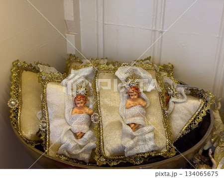 Nativity baby ornaments resting on golden trimmed cushions in display. Sacred Christmas symbolism, peaceful holiday devotion, traditional faith imagery and seasonal celebration craft Nativity baby ornaments resting on golden trimmed cushions in display. Sacred Christmas symbolism, peaceful holiday devotion, traditional faith imagery and seasonal celebration craft 134065675