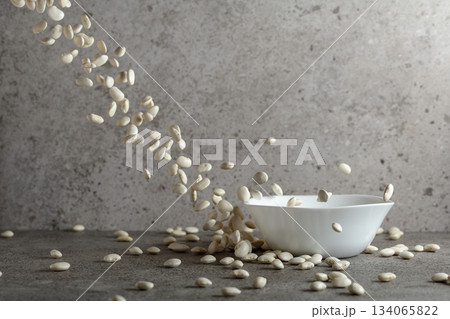 Dried white beans is poured in white ceramic bowl. Dried white beans is poured in white ceramic bowl. 134065822