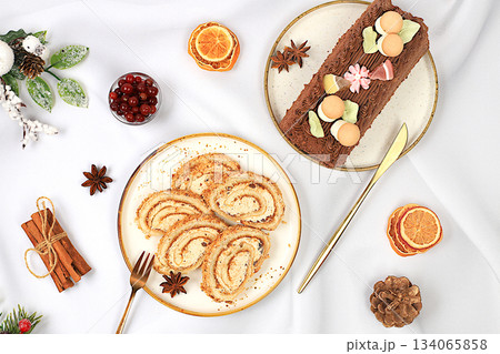 Homemade winter dessert, stollen, rolls or strudel with sweet cream filling, nuts, cinnamon, cranberries and poppy seeds. The concept of festive pastries, seasonal treats and cafe advertisements, Homemade winter dessert, stollen, rolls or strudel with sweet cream filling, nuts, cinnamon, cranberries and poppy seeds. The concept of festive pastries, seasonal treats and cafe advertisements, 134065858
