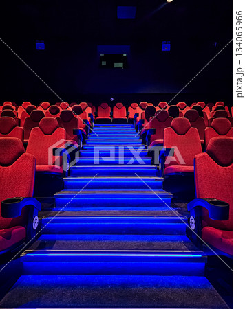 Photo taken from a low angle showing a blue-lit staircase surrounded by empty red cinema seats. Dramatic perspective highlights the theater interior and lighting. 134065966