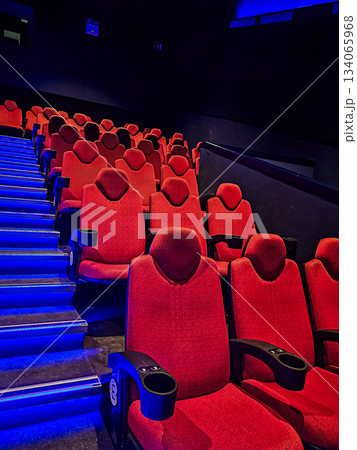 Photo showing half of a blue-lit staircase with red cinema seats alongside. The image highlights the theater interior, seating arrangement, and ambient lighting. 134065968