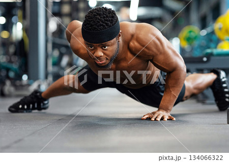 Push-up, press-up at gym concept. Motivated black guy bodybuilder doing some push-ups with one hand gym, panorama with copy space. African american shirtless muscular man working on triceps, biceps Push-up, press-up at gym concept. Motivated black guy bodybuilder doing some push-ups with one hand gym, panorama with copy space. African american shirtless muscular man working on triceps, biceps 134066322