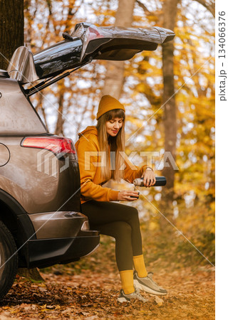 Female Sitting in Car Trunk in Autumn Forest 134066376