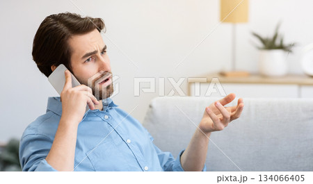 Discontented Guy Frowning Talking On Cellphone Sitting With Laptop, Having Computer Or Internet Connection Problem At Home. Displeased Customer Calling Hotline. Remote Work Issue. Selective Focus Discontented Guy Frowning Talking On Cellphone Sitting With Laptop, Having Computer Or Internet Connection Problem At Home. Displeased Customer Calling Hotline. Remote Work Issue. Selective Focus 134066405
