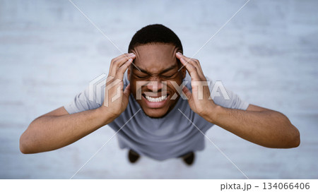 Top View Of Black Man Having Headache Suffering From Migraine Pain, Touching Aching Head Standing Indoors Over Gray Background. Male Health Problem Concept. Panorama, Selective Focus 134066406