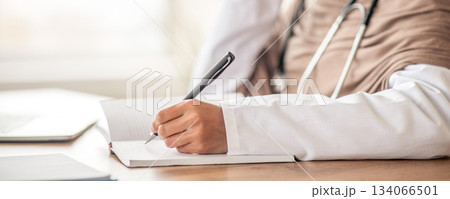 Doctor-patient relationships and communication concept. Cropped of female doctor smiling woman in hijab with stethoscope having conversation with patient on smartphone, taking notes, copy space 134066501