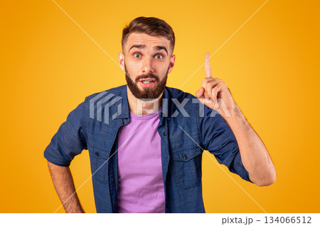 Great idea. Young Caucasian guy pointing finger upwards, gesturing eureka, having inspirational AHA moment on orange studio background. Millennial man finding solution to complicated problem 134066512