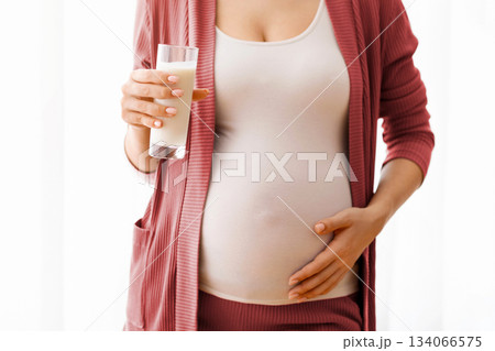Dairy Products During Pregnancy. Closeup Shot Of Pregnant Lady Holding Glass Of Milk, Unrecognizable Expectant Mother Standing Near Window At Home And Embracing Her Belly, Cropped Image, Free Space Dairy Products During Pregnancy. Closeup Shot Of Pregnant Lady Holding Glass Of Milk, Unrecognizable Expectant Mother Standing Near Window At Home And Embracing Her Belly, Cropped Image, Free Space 134066575