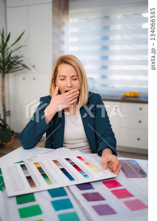 Tired designer yawning feeling burnout while working with color swatches 134066585
