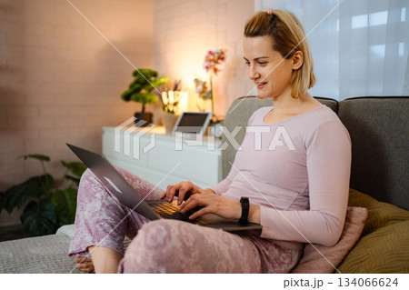 Woman working from home sitting on sofa using laptop 134066624