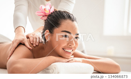 Relaxing Massage. Young asian woman getting classical body treatment at spa salon, lying on comfortable table with towel under head, beautiful korean lady pampering herself with beauty procedure. Relaxing Massage. Young asian woman getting classical body treatment at spa salon, lying on comfortable table with towel under head, beautiful korean lady pampering herself with beauty procedure. 134066873