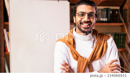 Online Distant Learning. Smiling Indian Teacher Guy Posing Near Blackboard With English Language Grammar Rules Standing At Home. Knowledge, Distance Teaching And Modern Education Concept. Copy Space Online Distant Learning. Smiling Indian Teacher Guy Posing Near Blackboard With English Language Grammar Rules Standing At Home. Knowledge, Distance Teaching And Modern Education Concept. Copy Space 134066931