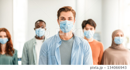 New Reality Rules, Epidemic Concept. Portrait of young man wearing protective medical mask standing with diverse group of international people in the blurred background, posing and looking at camera New Reality Rules, Epidemic Concept. Portrait of young man wearing protective medical mask standing with diverse group of international people in the blurred background, posing and looking at camera 134066943