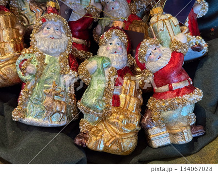 Vintage style Santa ornaments with glittered coats and pearl details arranged in festive display. Classic nostalgia, winter charm, handcrafted holiday decor and warm Christmas celebration feeling 134067028