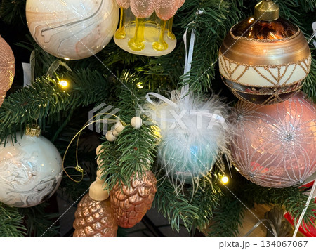Festive combination of baubles, pinecones and fluffy ornaments placed on a decorated Christmas tree. 134067067