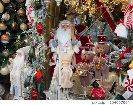 Santa with toy bears and festive ornaments surrounded by winter shop decor. Cozy Christmas spirit, nostalgia, childhood memories and magical celebration atmosphere 134067094