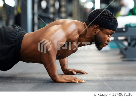 Push-ups, press-ups workout. Muscular african american shirtless guy sportsman building up muscles, black man training on floor at modern gym, doing push-ups and looking at copy space, panorama Push-ups, press-ups workout. Muscular african american shirtless guy sportsman building up muscles, black man training on floor at modern gym, doing push-ups and looking at copy space, panorama 134067130