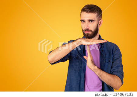 Millennial bearded guy showing TIME OUT or STOP gesture over orange studio background. Young Caucasian man taking break or pause, running late, facing deadline, expressing rejection Millennial bearded guy showing TIME OUT or STOP gesture over orange studio background. Young Caucasian man taking break or pause, running late, facing deadline, expressing rejection 134067132