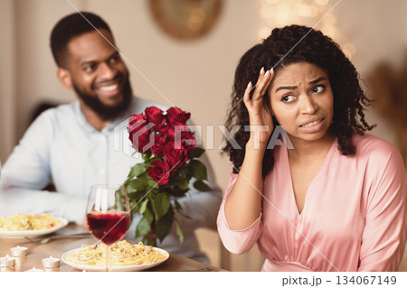 Bad Date. African American Couple Having Unsuccessful Meeting In Restaurant, Funny Disappointed Shoked Black Woman Feeling Embarrassment Covering Face, Man Giving Her Bouquet Of Red Roses 134067149