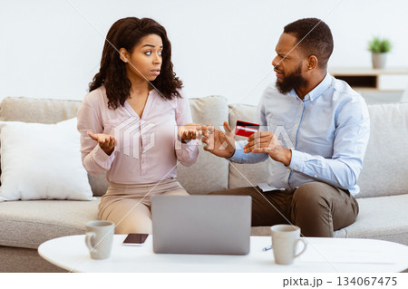 Stressed unhappy black couple arguing about huge expenses, angry man holding credit card blaming woman of overspending debt, family having conflict fight about wasting money. Financial problem at home Stressed unhappy black couple arguing about huge expenses, angry man holding credit card blaming woman of overspending debt, family having conflict fight about wasting money. Financial problem at home 134067475