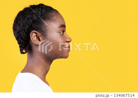 Profile Portrait Of Black Young Lady Posing Looking Aside At Free Space For Text Standing In Studio Over Yellow Background. Side View Shot Of Beautiful African American Woman 134067514