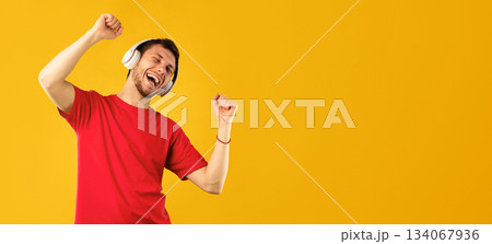 Life Is Good. Portrait of positive carefree guy listening to music with closed eyes, wearing wireless headset and dancing, relaxing and enjoying song isolated over blue studio background Life Is Good. Portrait of positive carefree guy listening to music with closed eyes, wearing wireless headset and dancing, relaxing and enjoying song isolated over blue studio background 134067936