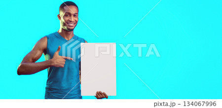 Sportsman Pointing Finger At Blank White Poster Advertising Gym Over Turquoise Blue Background In Studio. Mockup Sportsman Pointing Finger At Blank White Poster Advertising Gym Over Turquoise Blue Background In Studio. Mockup 134067996
