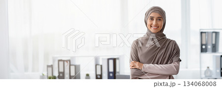 Business Career For Muslim Woman. Portrait Of Confident Arabic Businesswoman In Hijab Standing With Folded Arms Near Her Workplace In Office, Copy Space Business Career For Muslim Woman. Portrait Of Confident Arabic Businesswoman In Hijab Standing With Folded Arms Near Her Workplace In Office, Copy Space 134068008