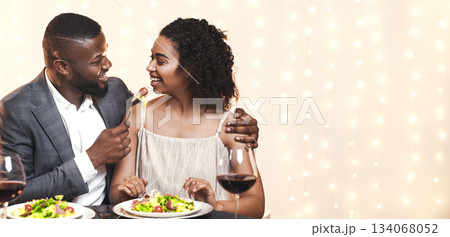 Beautiful young black couple in love feeding each other and smiling while spending time at restaurant Beautiful young black couple in love feeding each other and smiling while spending time at restaurant 134068052