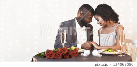 Beautiful african man and woman in love cuddling during valentine dinner, holding hands Beautiful african man and woman in love cuddling during valentine dinner, holding hands 134068086