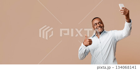 Modern african middle aged man making selfie and gesturing like, orange background, free space Modern african middle aged man making selfie and gesturing like, orange background, free space 134068141