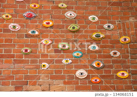 Various eye shapes in different colors are mounted on a red brick wall Various eye shapes in different colors are mounted on a red brick wall 134068151