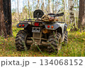 quad bike or ATV or quadbike stands in green tall grass in forest on summer day 134068152