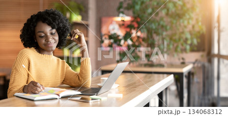 Dreamy black girl writing down thoughts while spending time at cafe, using laptop, copy space Dreamy black girl writing down thoughts while spending time at cafe, using laptop, copy space 134068312