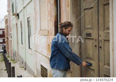 Casual individual uses key to open aged apartment door on city street Casual individual uses key to open aged apartment door on city street 134070224