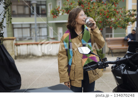 Peaceful moment of woman enjoying coffee outdoors amid cityscape 134070248