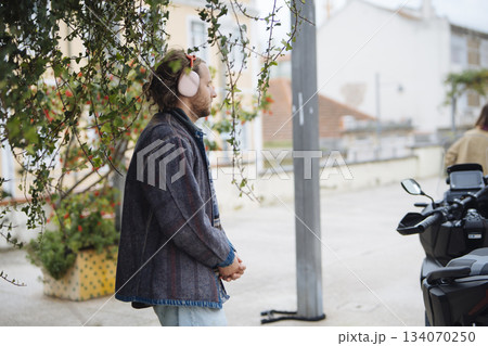 man with headphones listening near scooter, street soundtrack man with headphones listening near scooter, street soundtrack 134070250