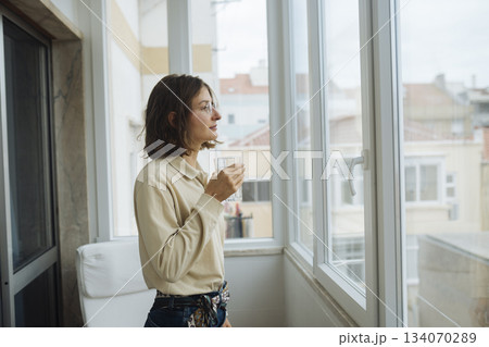 Serene woman reviewing her schedule with city view nearby Serene woman reviewing her schedule with city view nearby 134070289