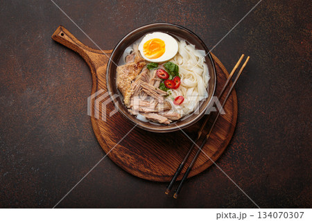 Asian soup rice noodles duck meat egg chopsticks ramen bowl dark rustic background Asian soup rice noodles duck meat egg chopsticks ramen bowl dark rustic background 134070307