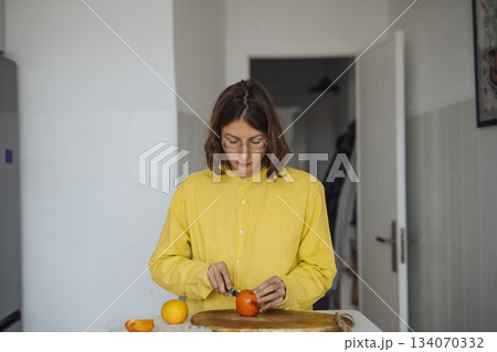 Young lady carefully carves fruit in cozy morning setting Young lady carefully carves fruit in cozy morning setting 134070332